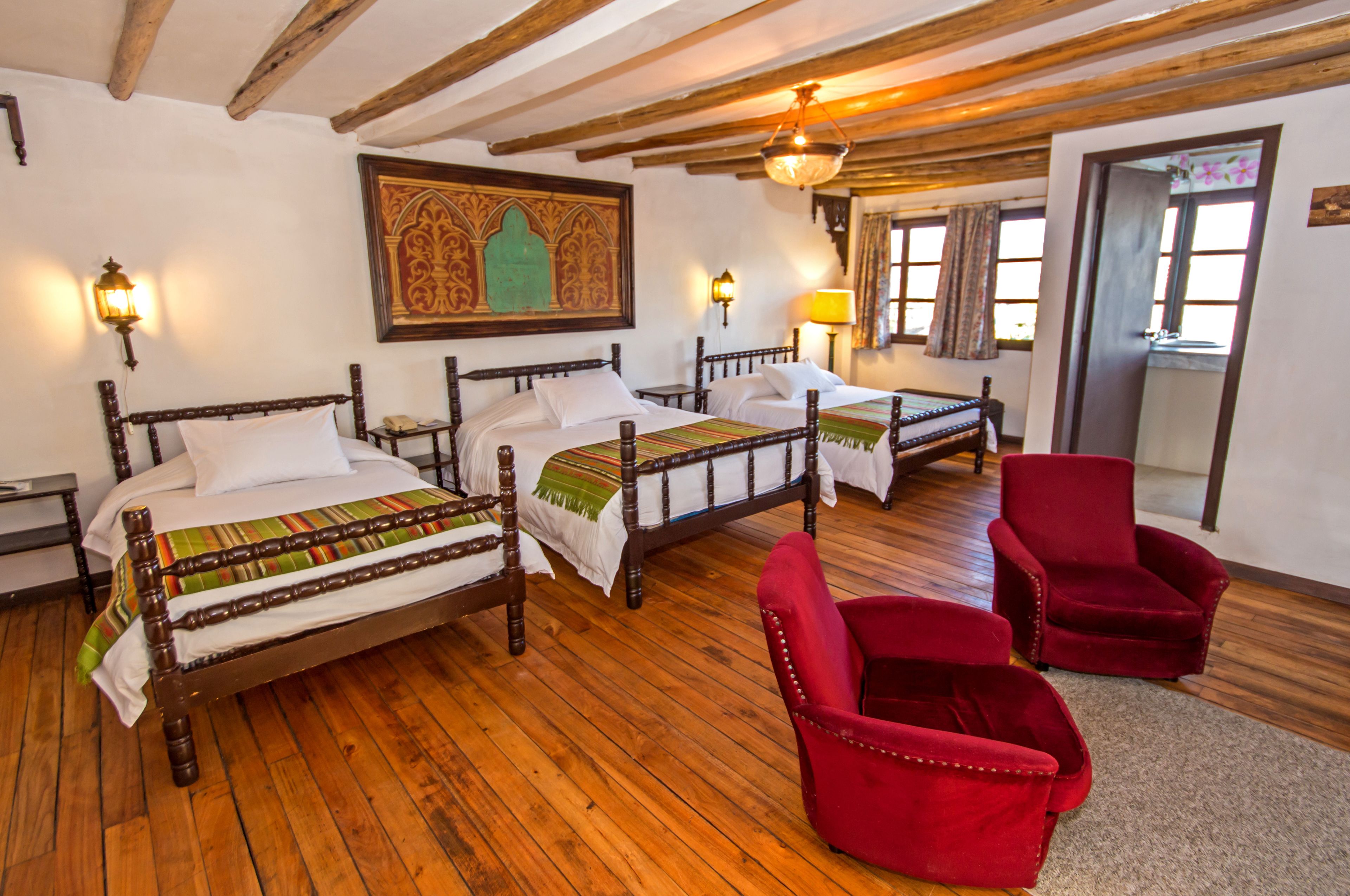 A room with two wooden beds, a red chair, and a wooden floor.