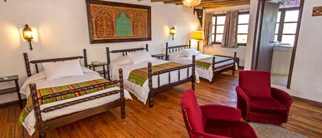 A room with two wooden beds, a red chair, and a wooden floor.