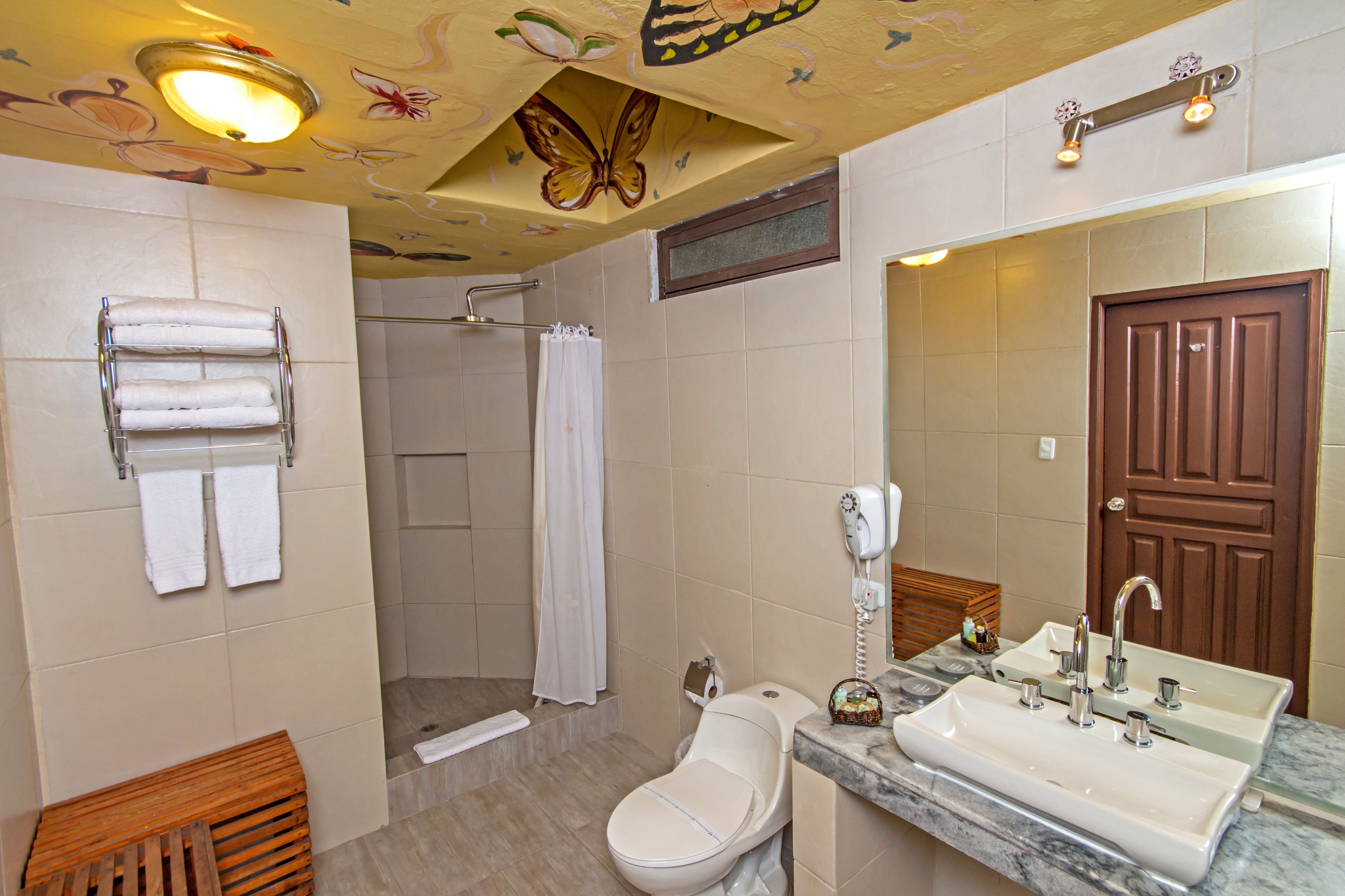 A bathroom with a shower, toilet, sink, and towel rack.