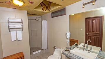 A bathroom with a shower, toilet, sink, and towel rack.
