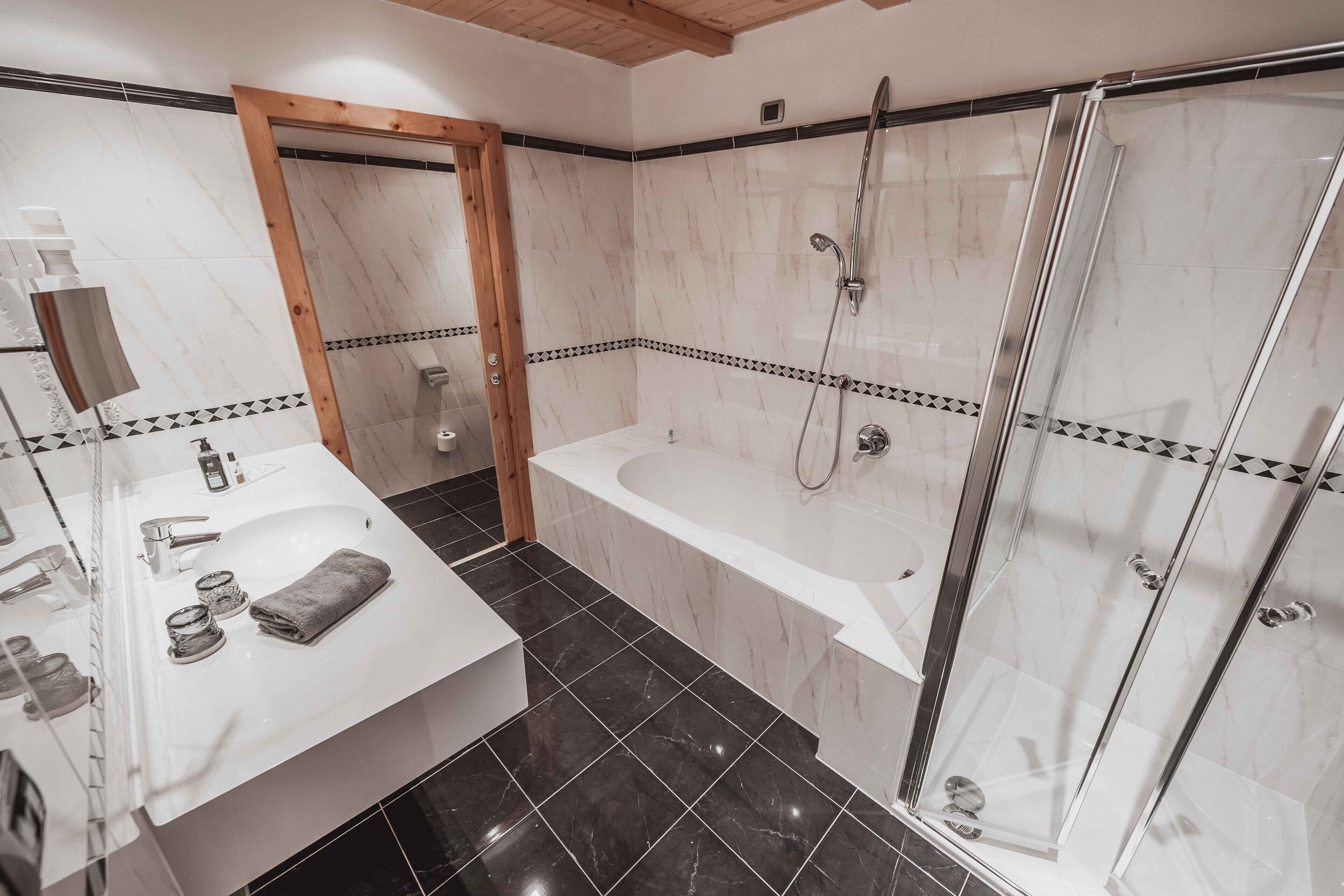 A modern bathroom with a white sink, mirror, and a glass-enclosed shower area.