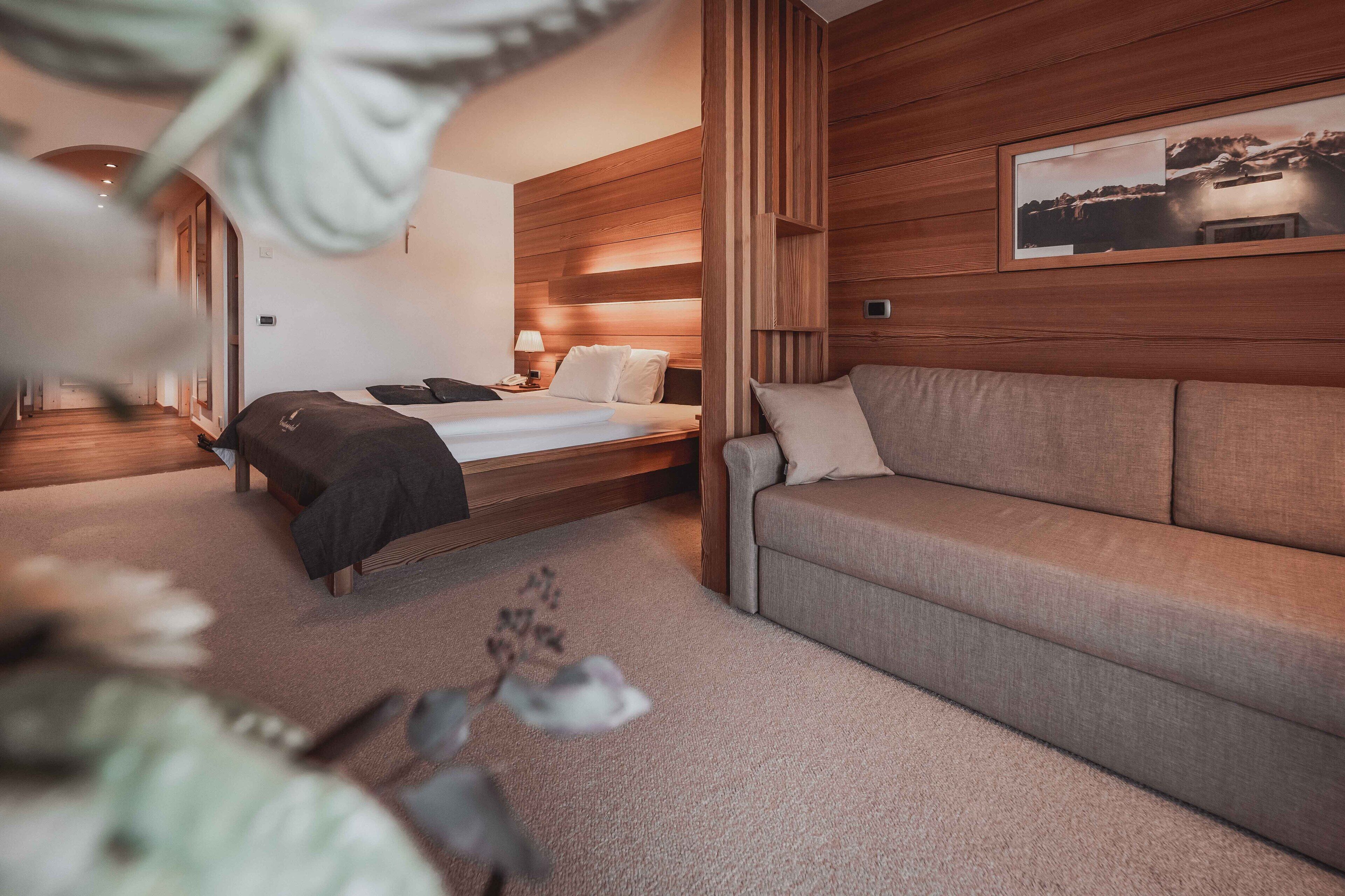 Una camera d'albergo moderna con un letto, una poltrona e una testiera in legno.