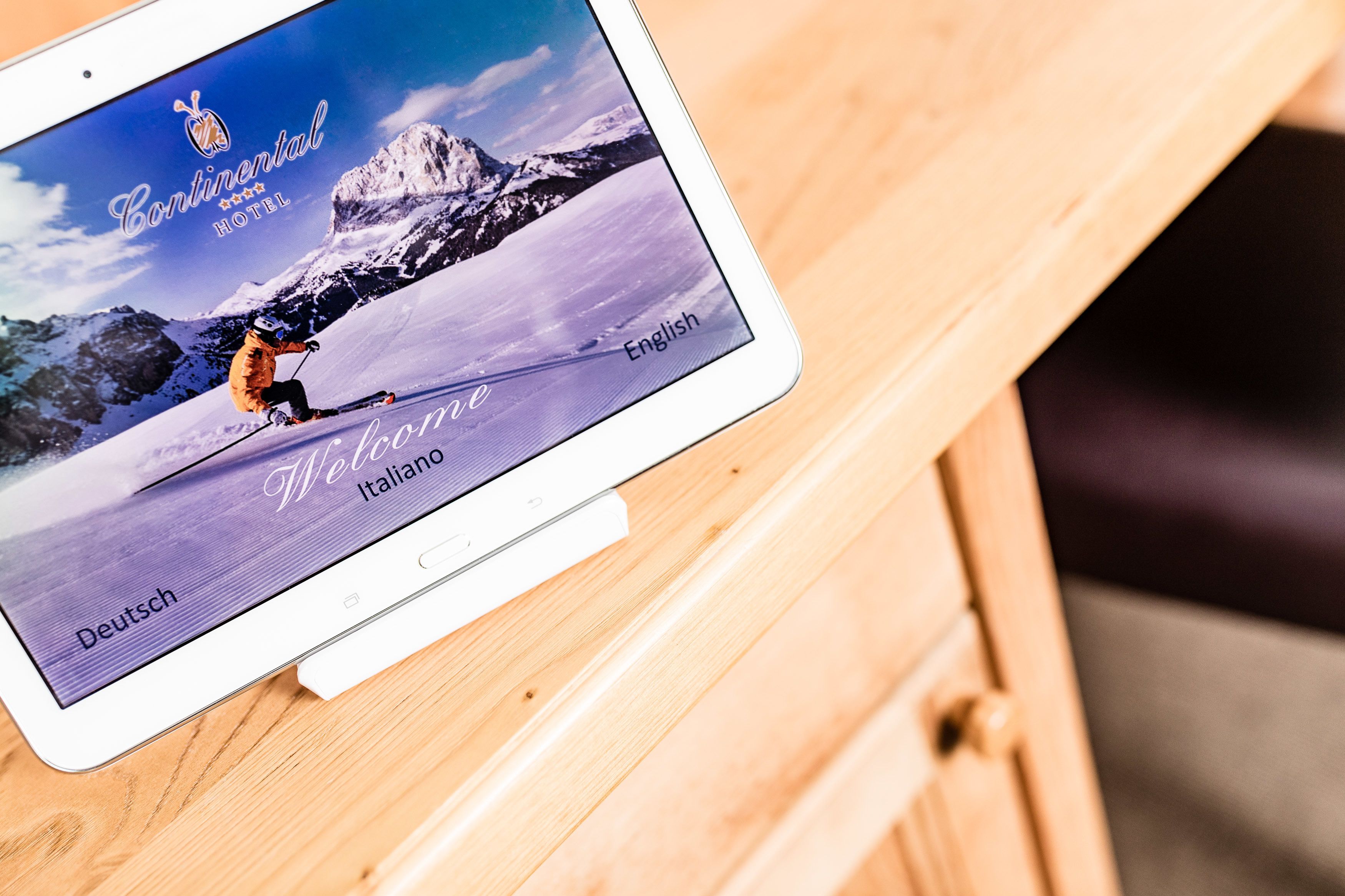Ein Tablet zeigt einen Begrüßungsbildschirm für das Continental Hotel vor einer Skigebietskulisse.