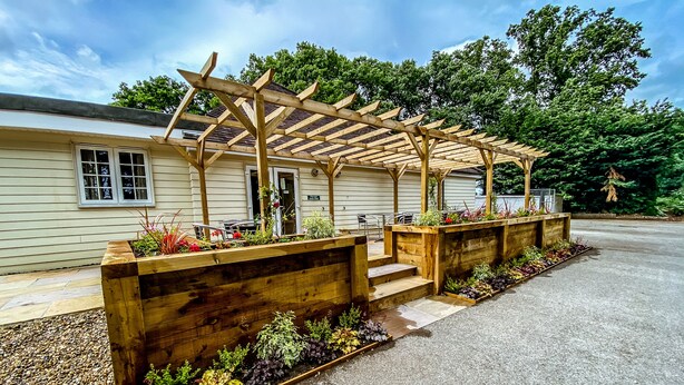 Un patio cubierto con bancos de madera y macetas con diversas plantas.