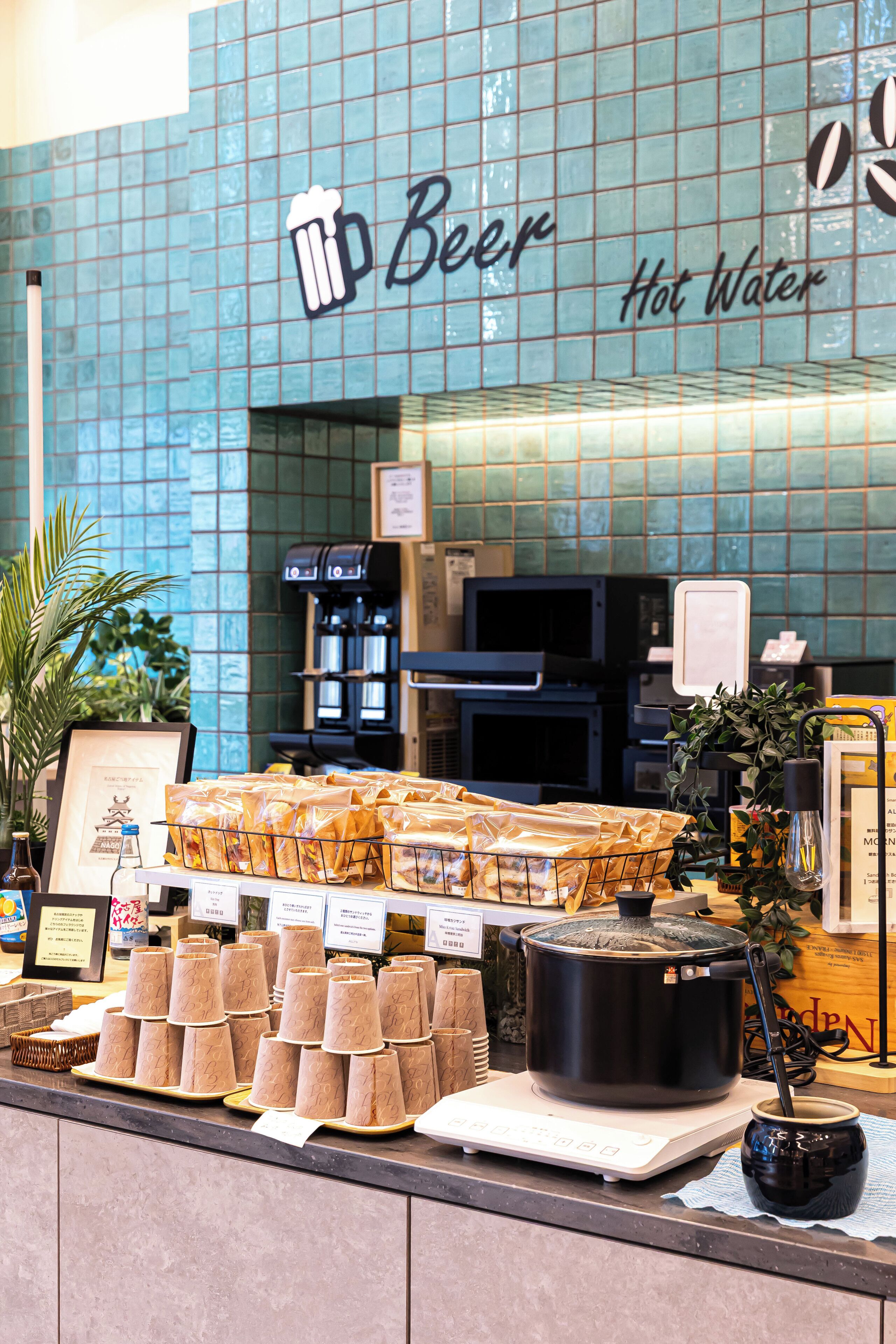 Una barra con un letrero que dice 'Cerveza Agua Caliente' y una exhibición de productos alimenticios envasados.