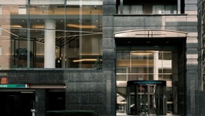 Um edifício moderno com entrada de vidro, porta giratória e uma placa com a inscrição "Prince Smart Inn".