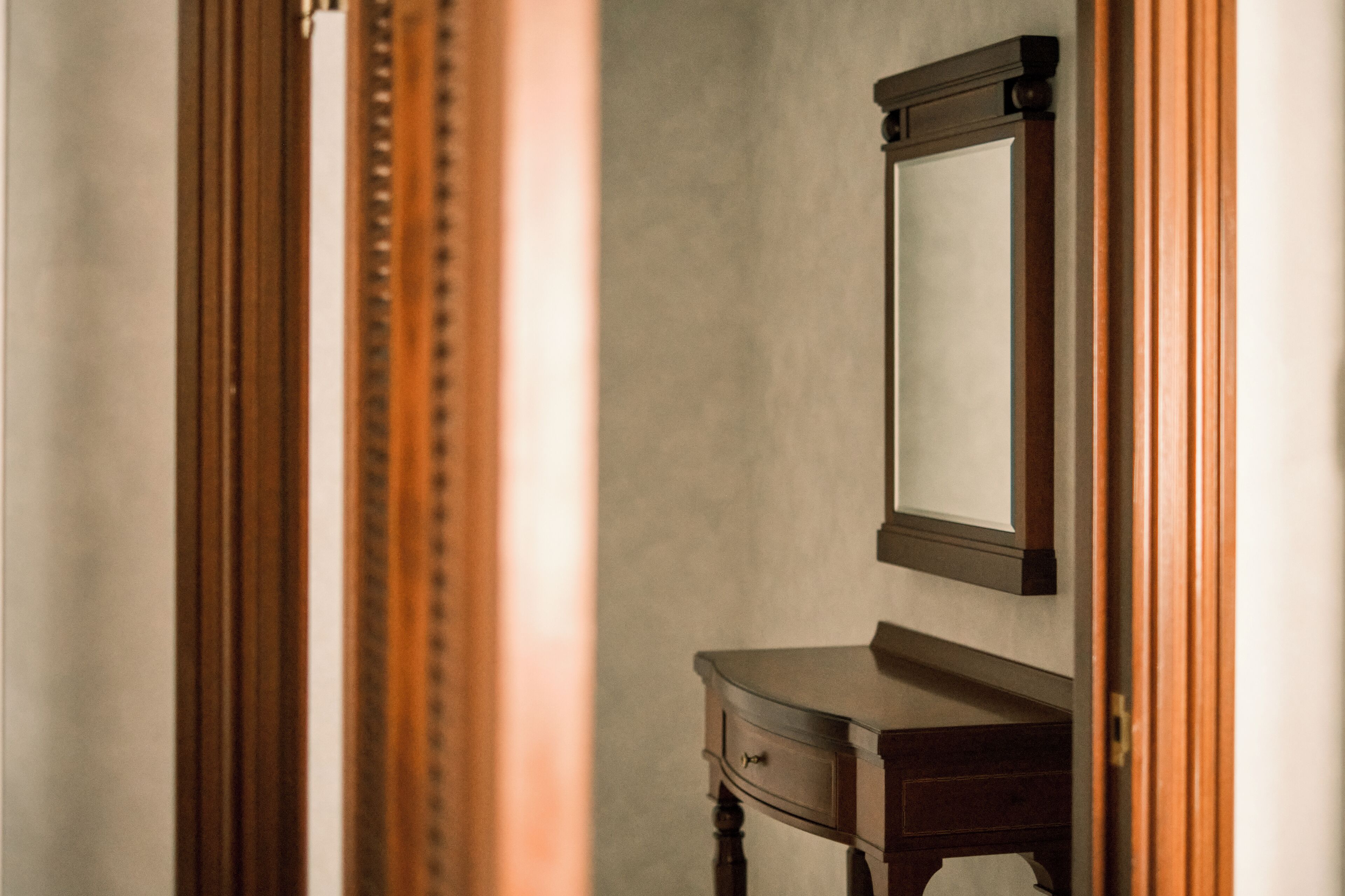 Une commode en bois, dotée d’un miroir et d’un tiroir, est placée contre un mur uni.