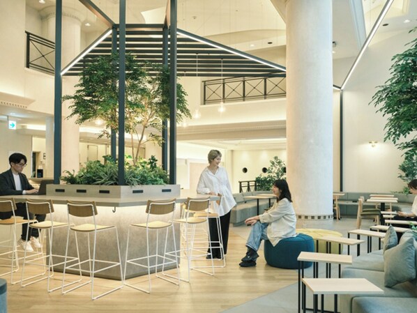 A spacious indoor area with multiple seating arrangements, including tables and chairs, and a central plant area.