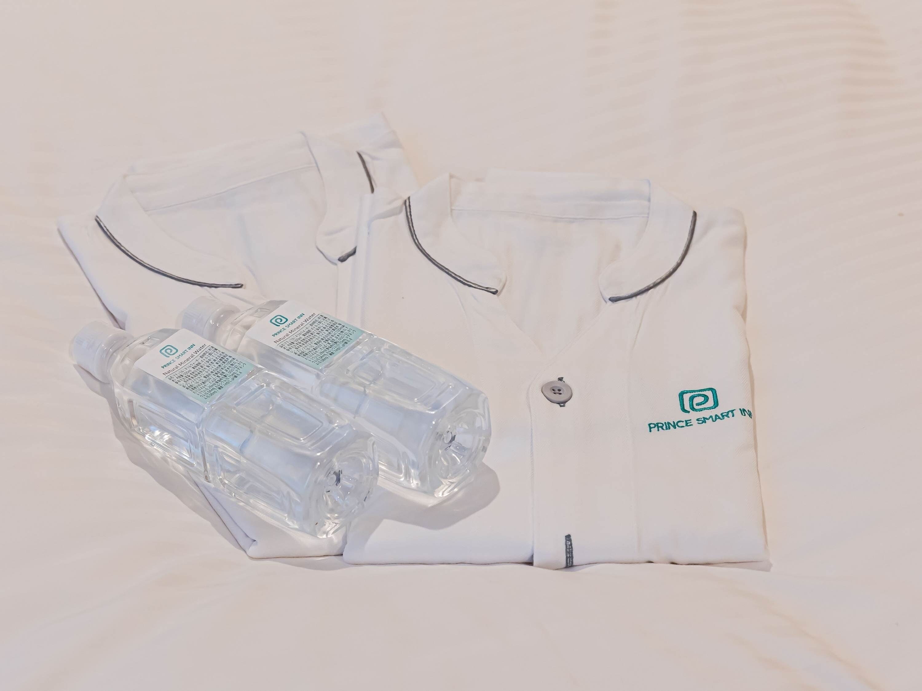 A neatly folded white shirt with a logo and two plastic water bottles.