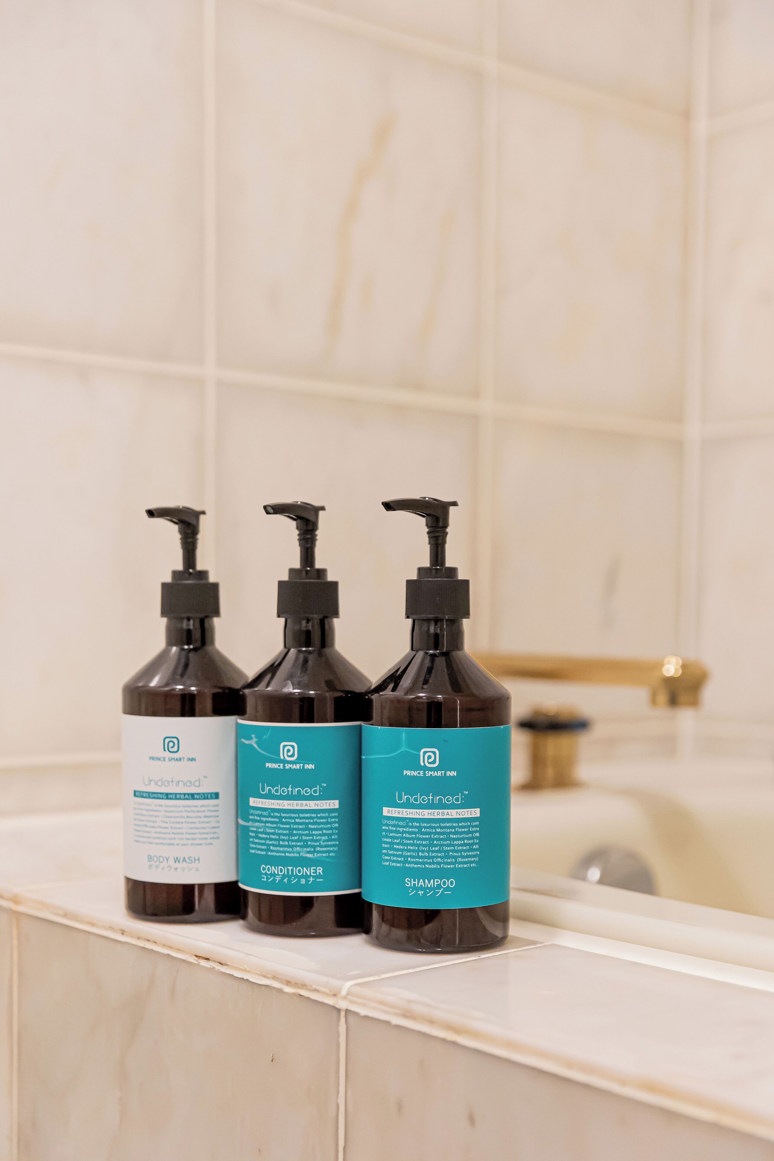 Three bottles of Prince Smart Inn Undetermined body wash, conditioner, and shampoo on a bathroom counter.