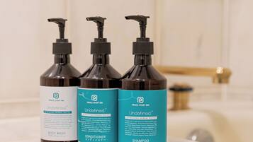 Three bottles of Prince Smart Inn Undetermined body wash, conditioner, and shampoo on a bathroom counter.