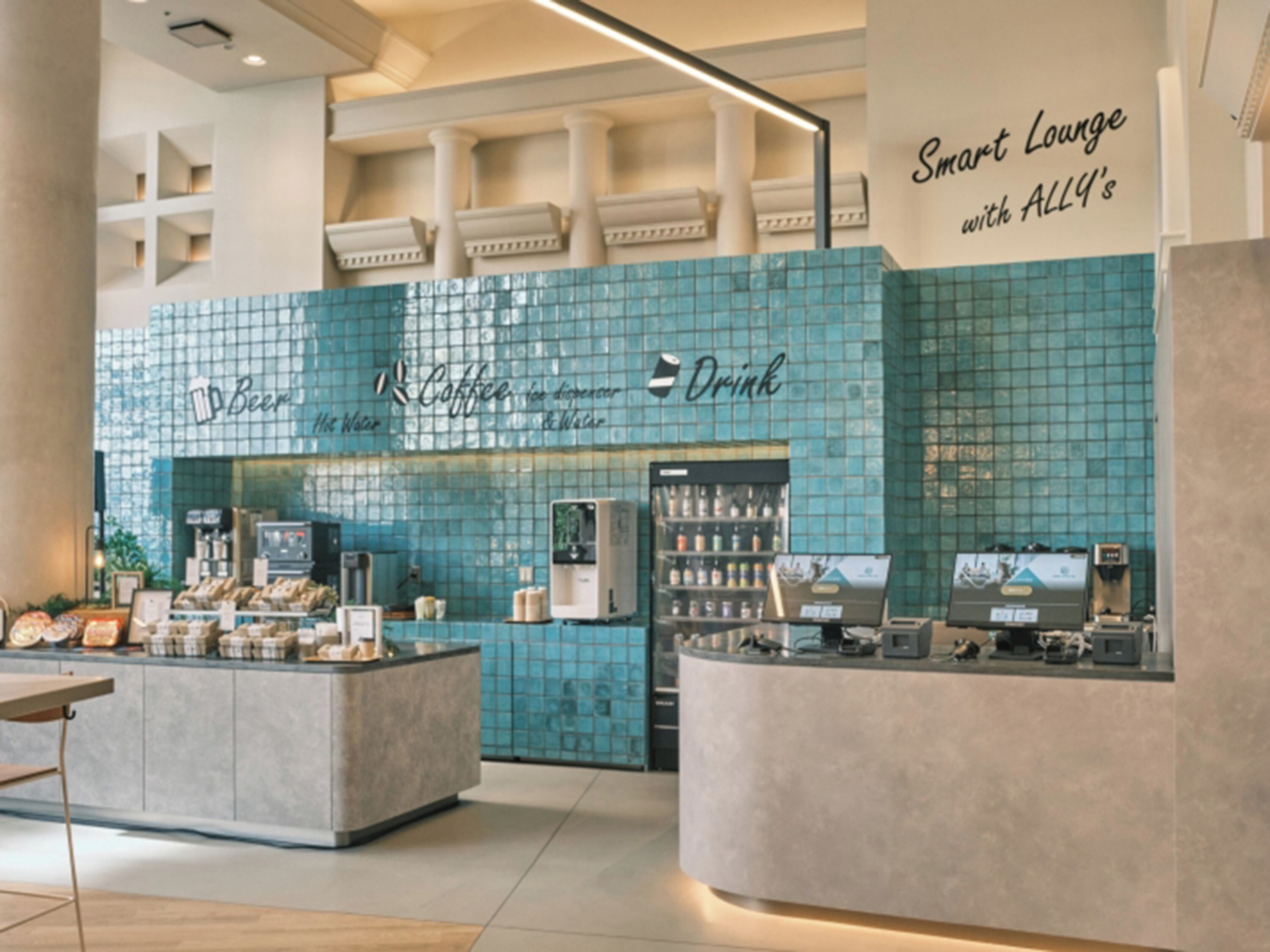 A modern coffee shop with a blue-tiled wall, a counter with a coffee machine, and a sign reading "Smart Lounge with ALL4's".