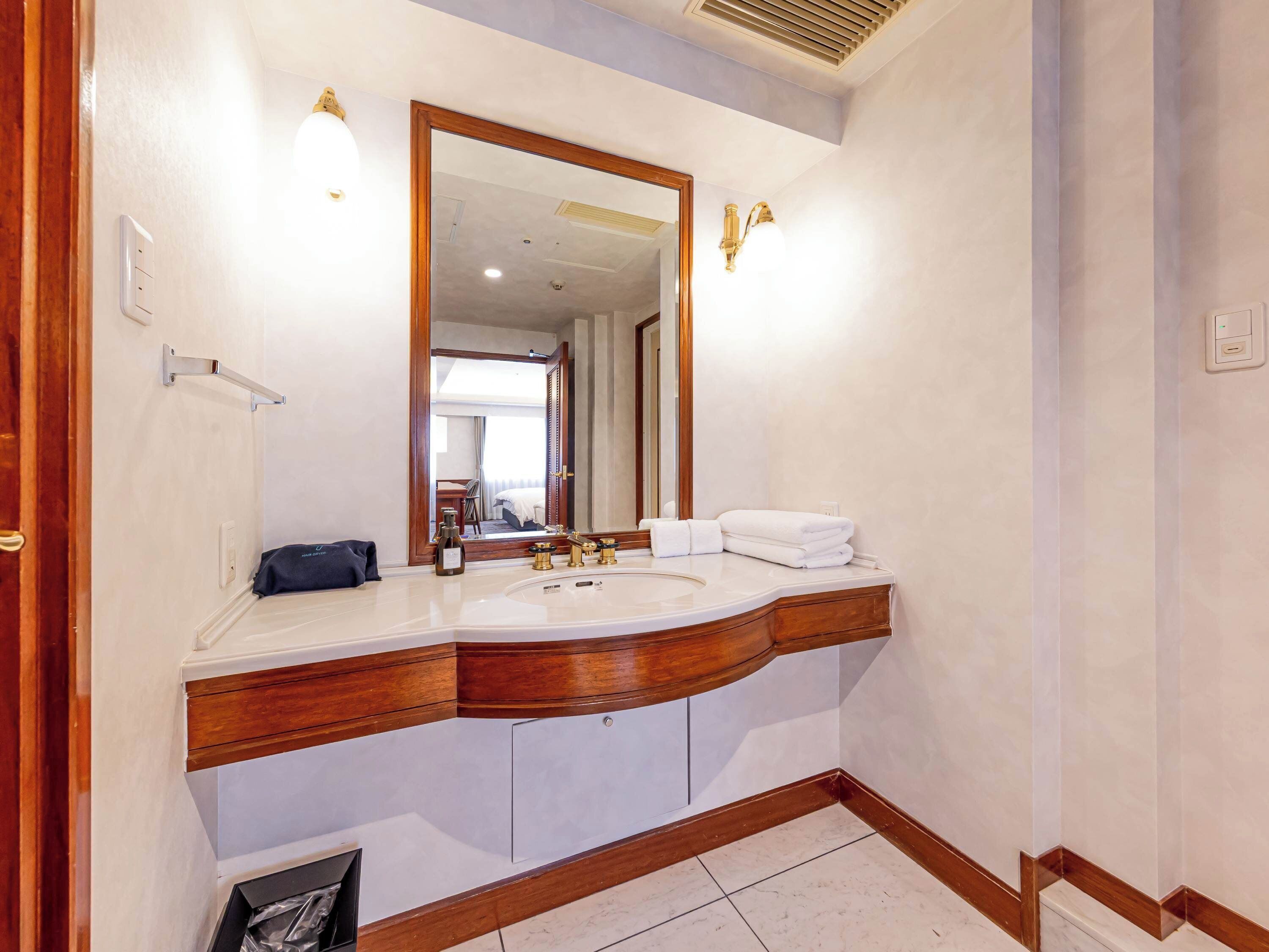 A bathroom with a large mirror, a sink, and a towel rack.