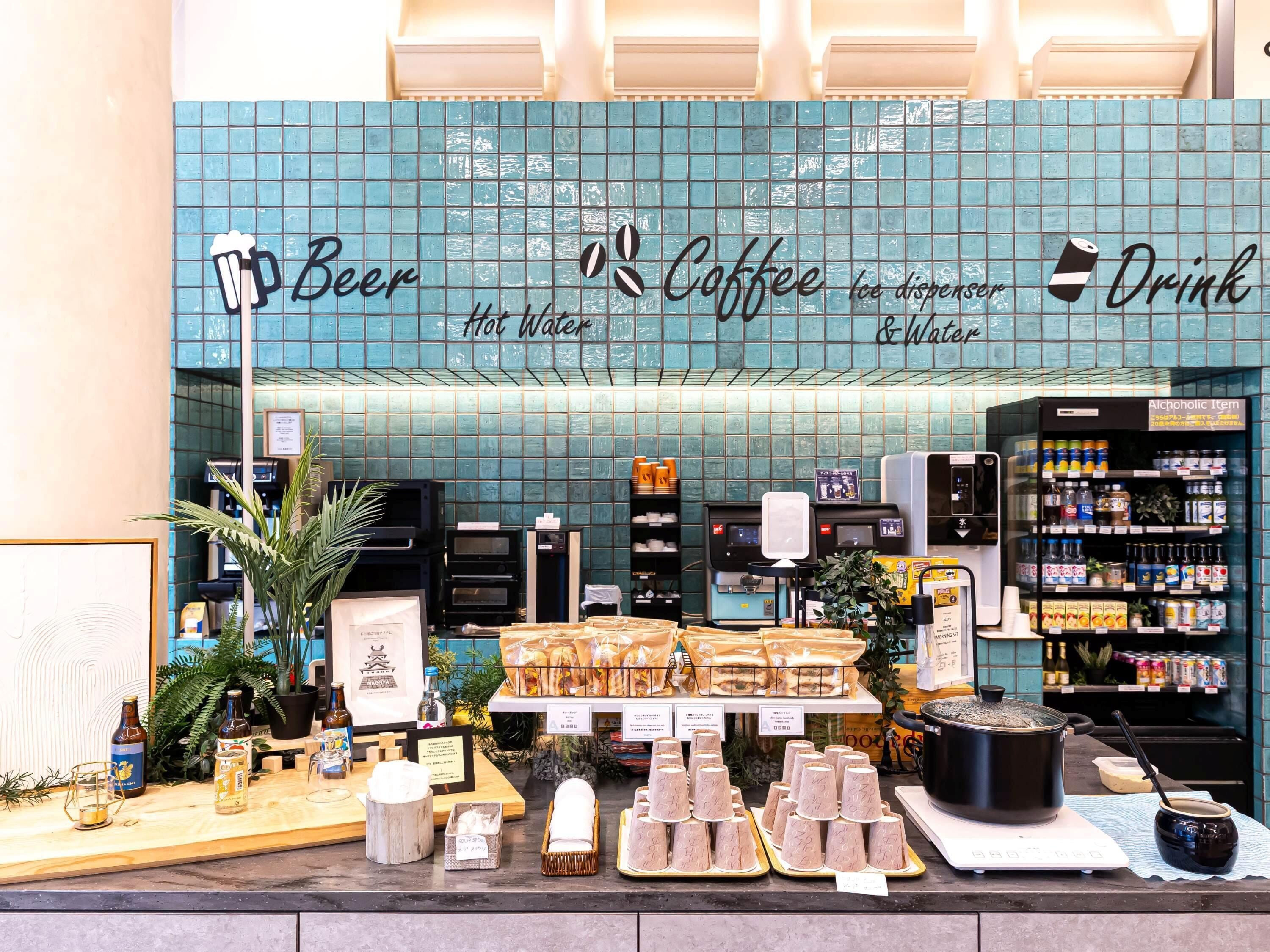 Un café avec un mur recouvert de carreaux, une machine à café, un robinet à bière et un choix de boissons et d’en-cas.