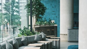 Espaço de estar interno moderno com sofá, mesas e uma planta.