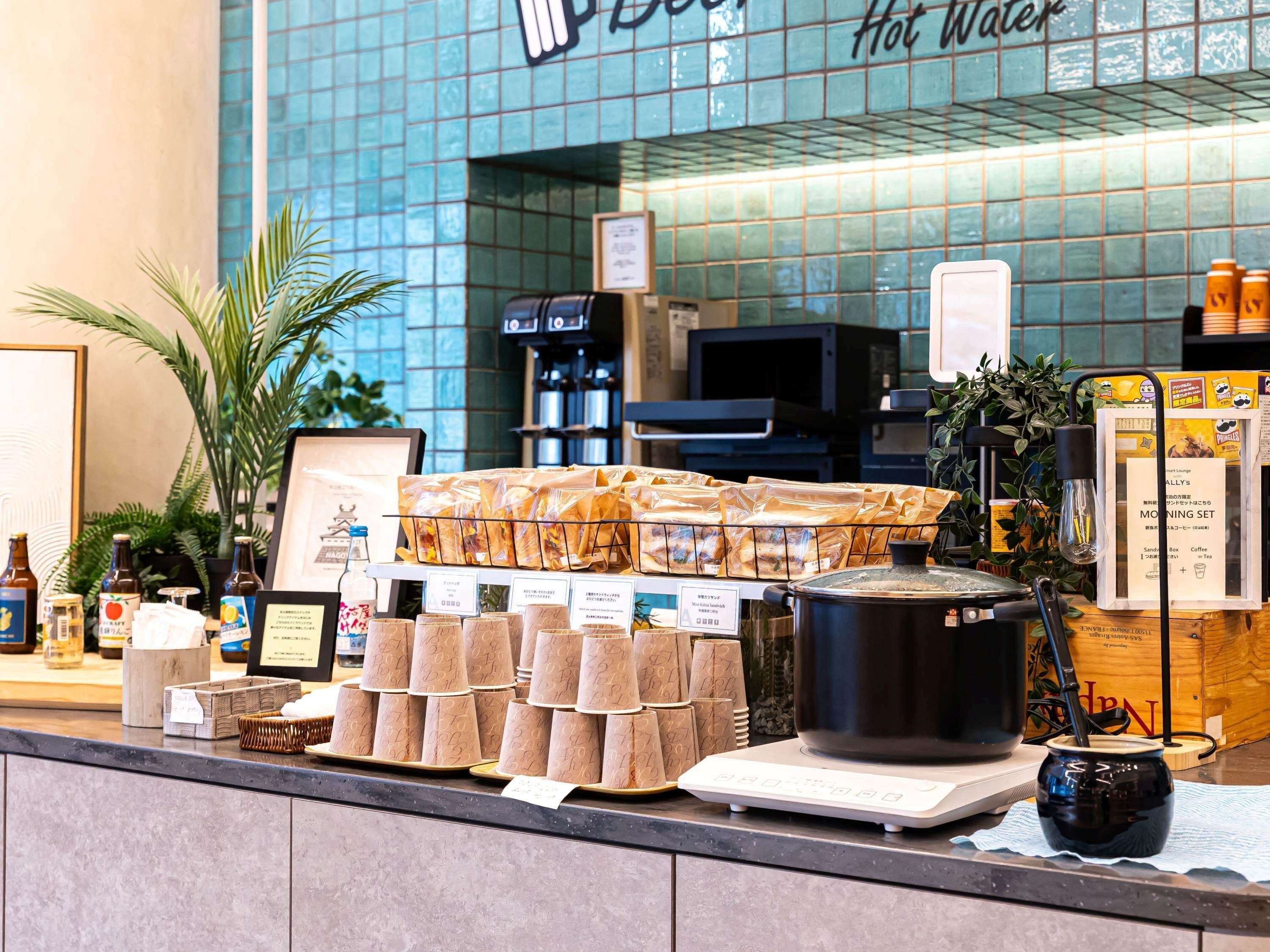 A coffee shop counter with a variety of coffee beans, paper cups, and a coffee pot.