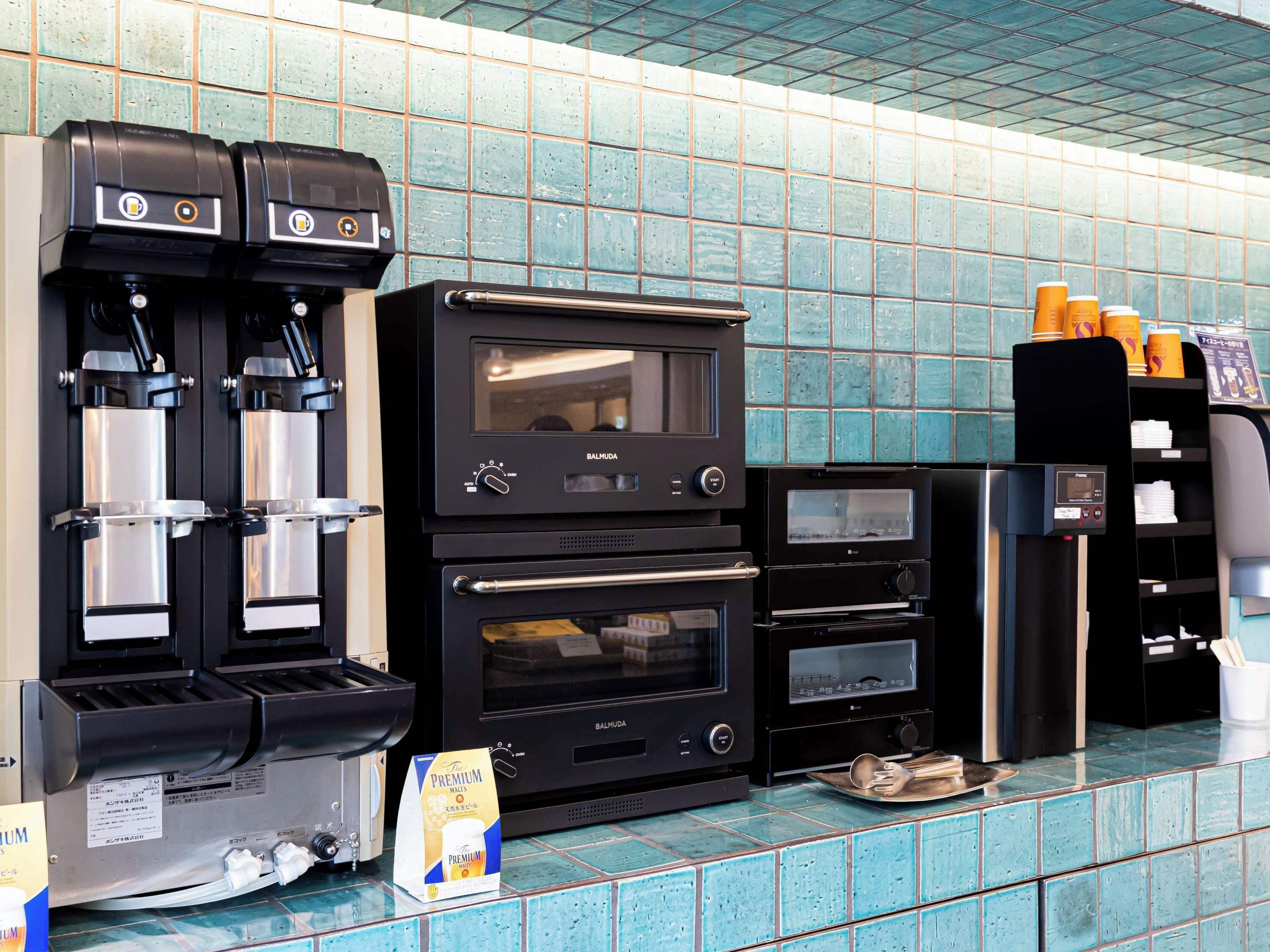 Una máquina de café, un microondas y un dispensador de café en una cocina industrial.
