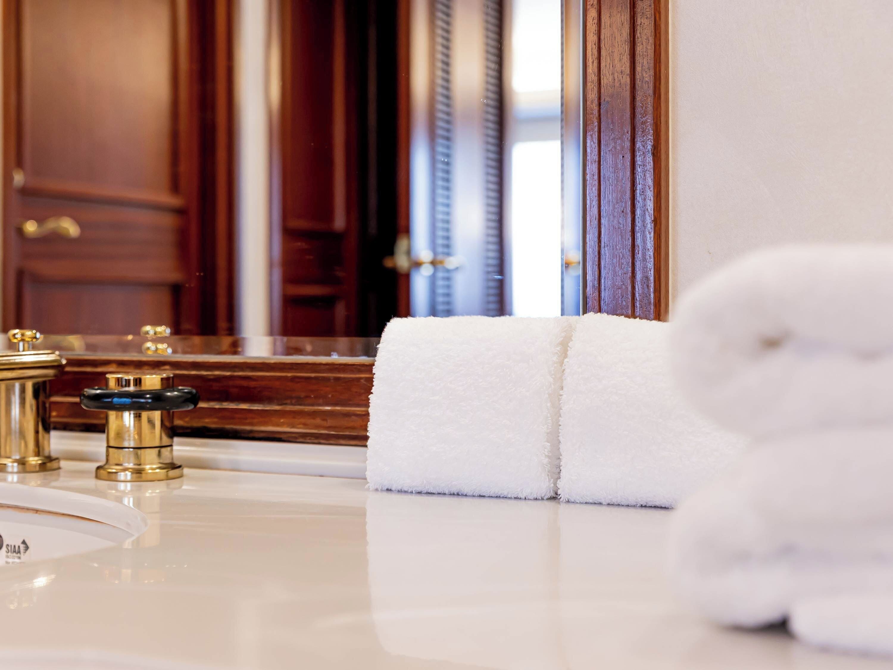 A bathroom with a white bathtub, a gold faucet, and a towel on the counter.