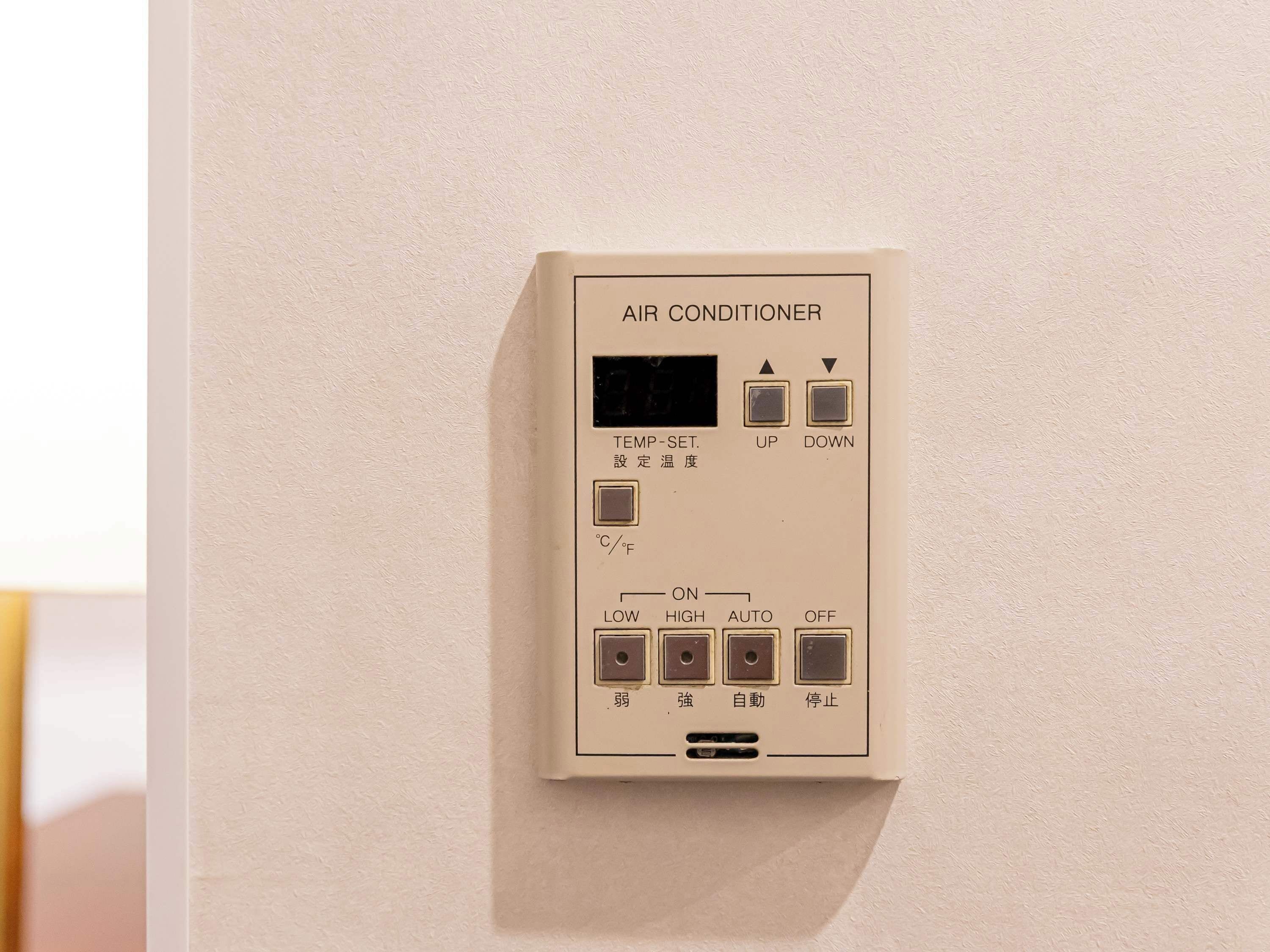 A wall-mounted air conditioner with temperature settings, a digital display, and control buttons for up, down, low, high, auto, and off modes.