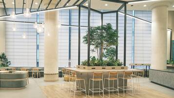 A modern indoor space with a central island, bar stools, and seating areas.