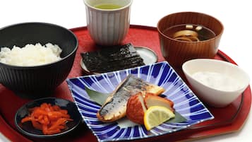 A tray with a variety of Japanese dishes including rice, fish, pickled vegetables, and a small bowl of soup.
