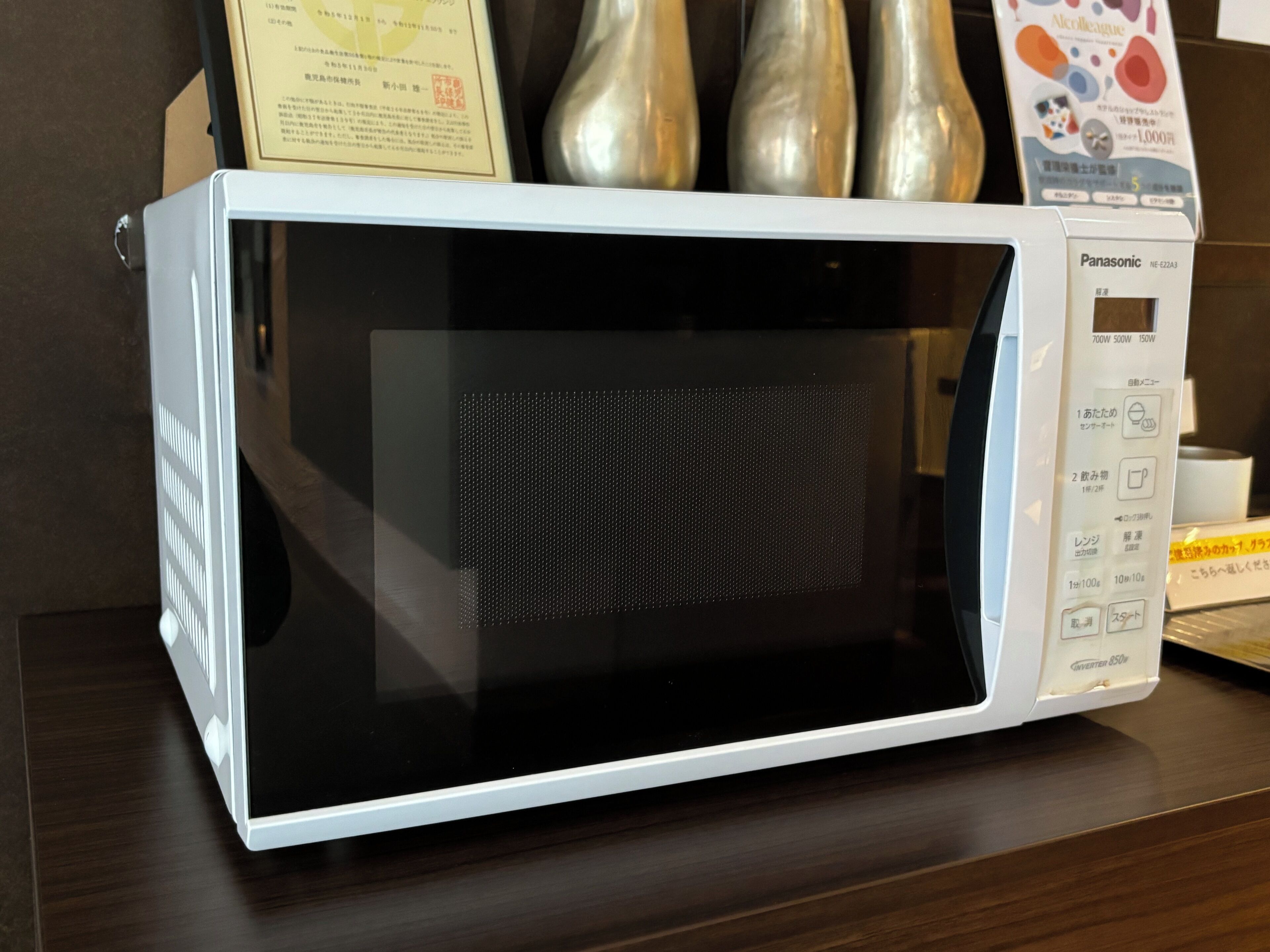 Un four à micro-ondes Panasonic blanc, doté d’un écran numérique et d’un panneau de commande, posé sur une surface en bois.