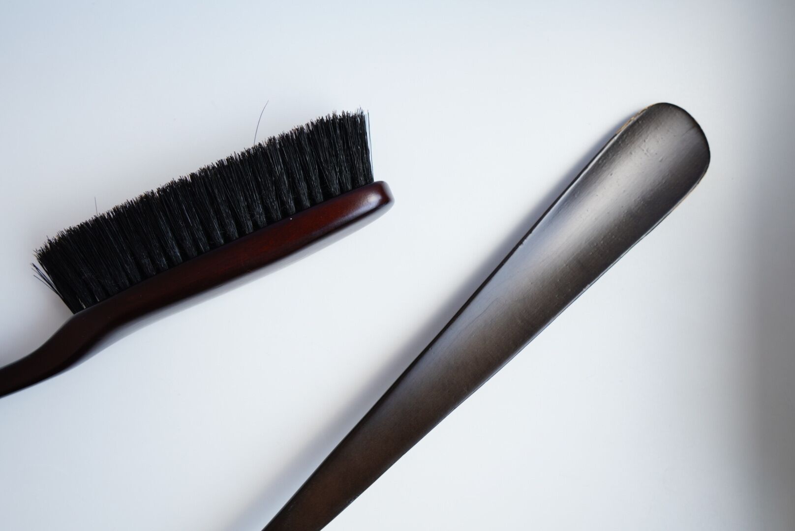 Un cepillo para el cabello y una plancha para alisar sobre una superficie blanca.