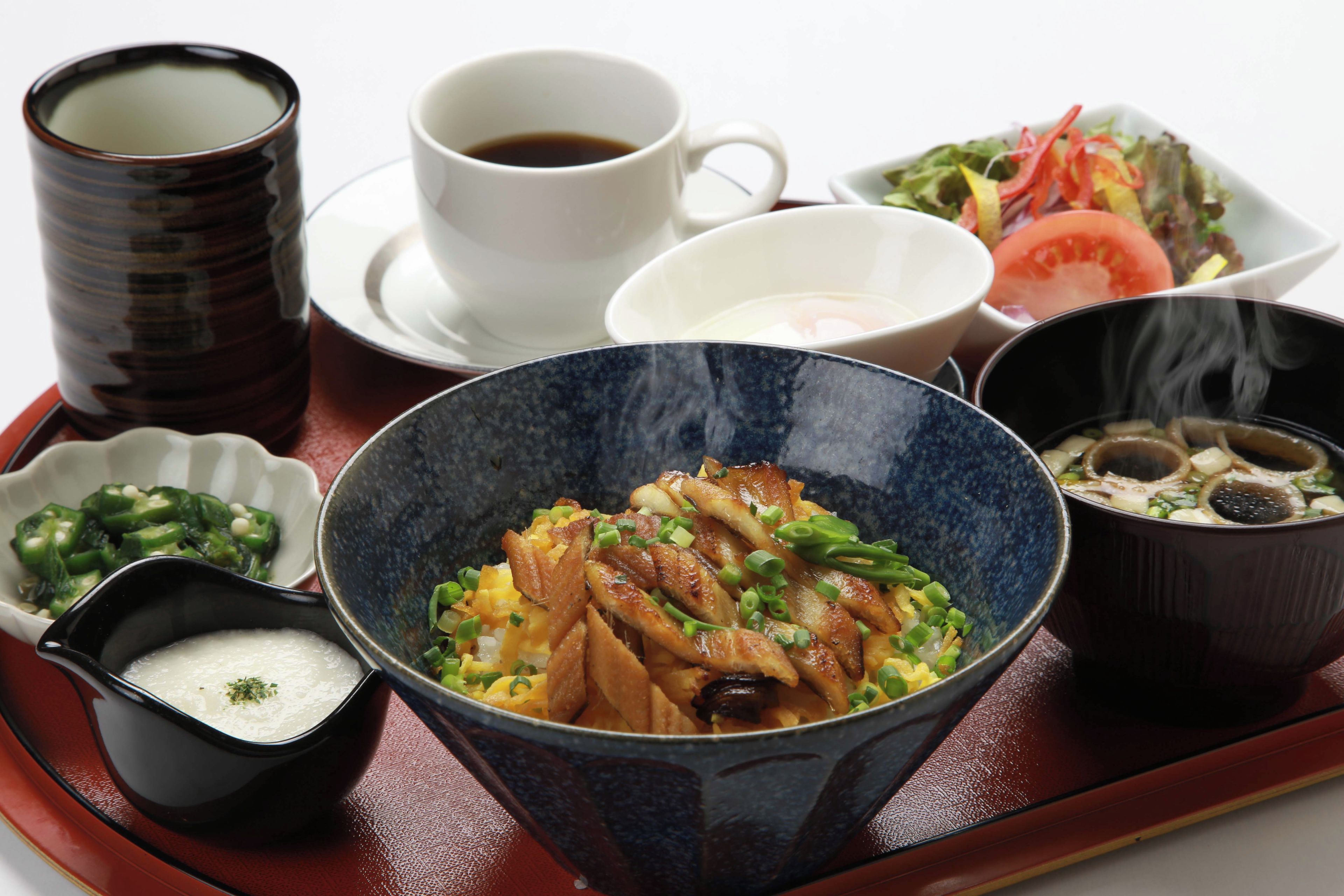 A tray with various dishes including a bowl of rice, a bowl of soup, a cup of tea, a small bowl of pickled vegetables, and a plate of salad.