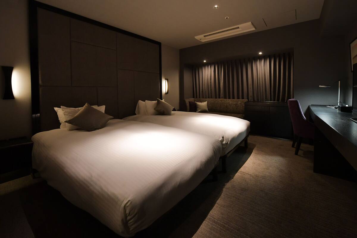A modern hotel room with a large bed, a desk, and a chair.