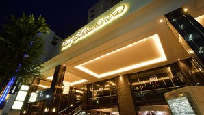 Un hotel con un letrero iluminado llamativo, diseño arquitectónico moderno y una entrada visible con escaleras.