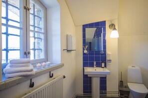 Bathroom features a window, sink, mirror, toilet, and radiator.
