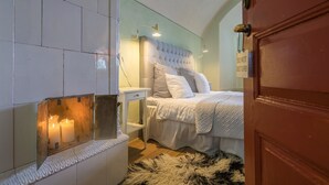 Un dormitorio con cama, mesita de noche y estante en la pared con velas.
