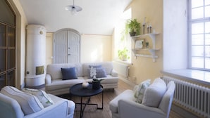 Un salón acogedor con un sofá blanco, una mesita redonda y una estantería con plantas.