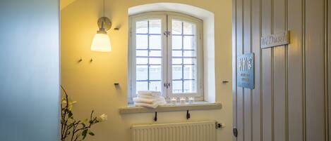 A bathroom with a window, a radiator, and a towel rack.
