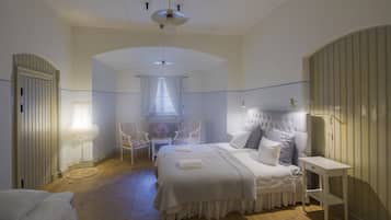 Un dormitorio con una cama grande, una silla, una mesita de noche y una ventana con cortinas.