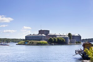 Explore a historic castle situated by a serene body of water, featuring multiple towers and a robust structure.