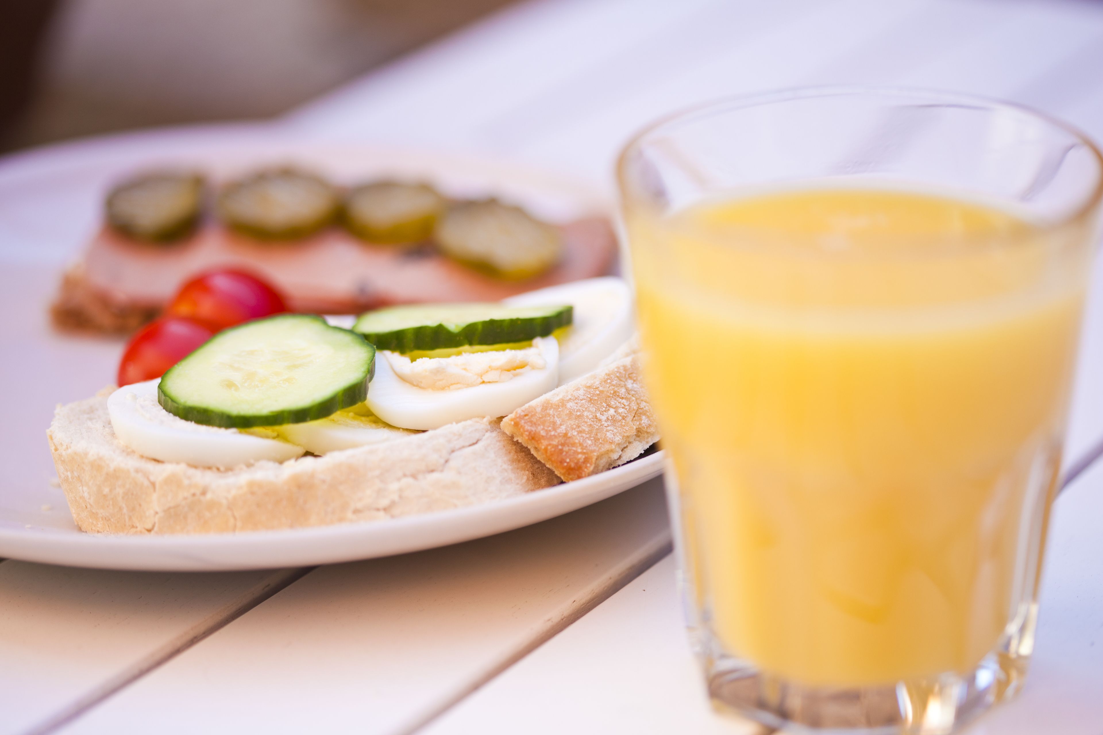 Une assiette avec un sandwich et un verre de jus d’orange.