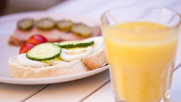 Une assiette avec un sandwich et un verre de jus d’orange.