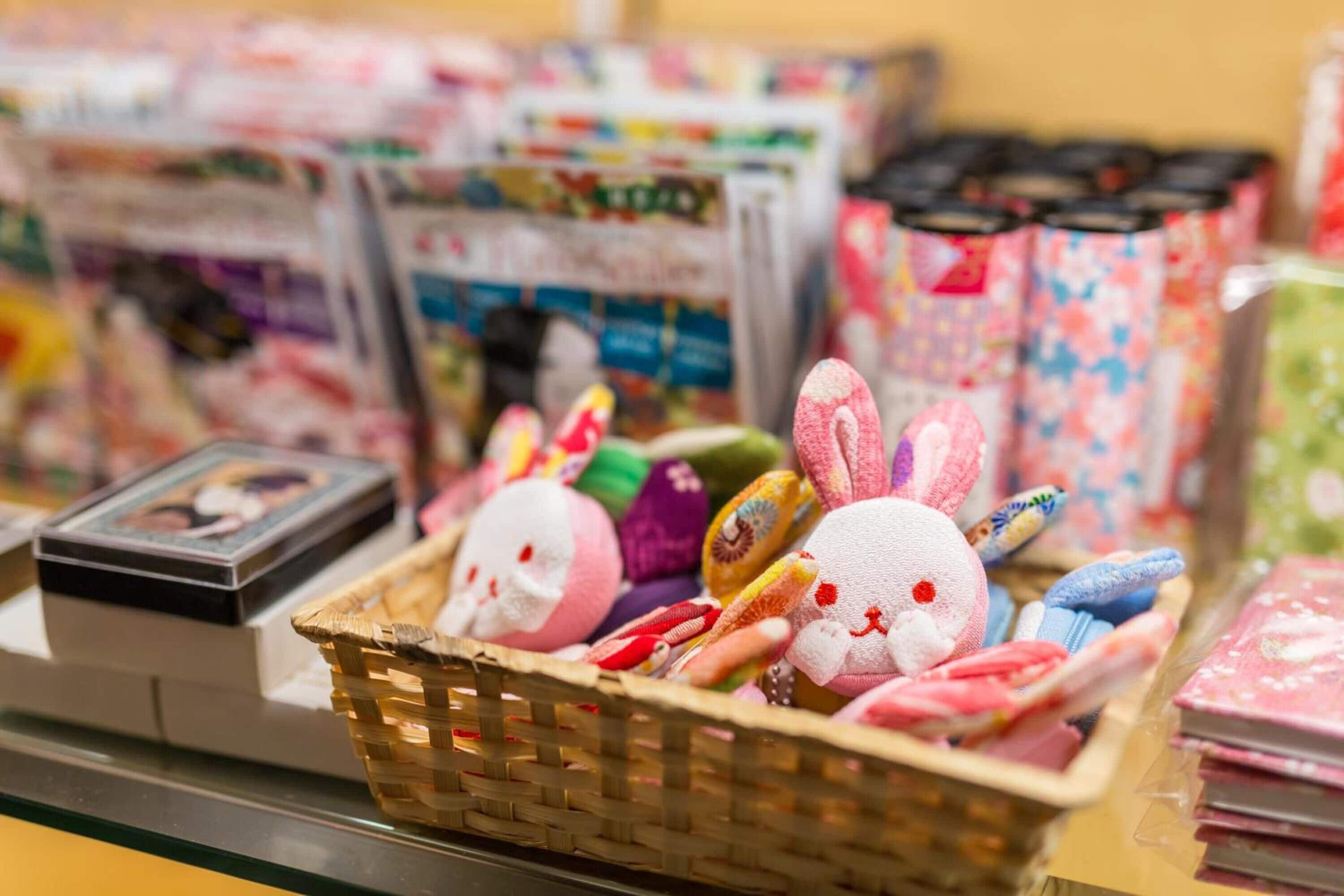 Un présentoir rempli de peluches et d’articles de papeterie, notamment un panier de lapins en peluche, ainsi que divers livres et cahiers.