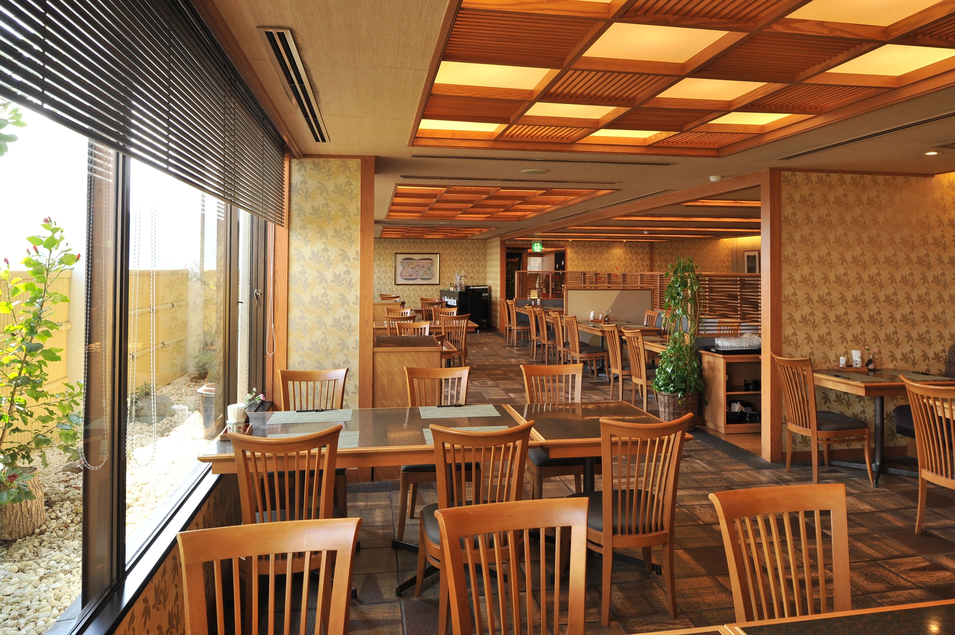 A restaurant with wooden furniture, large windows, and a tiled floor.