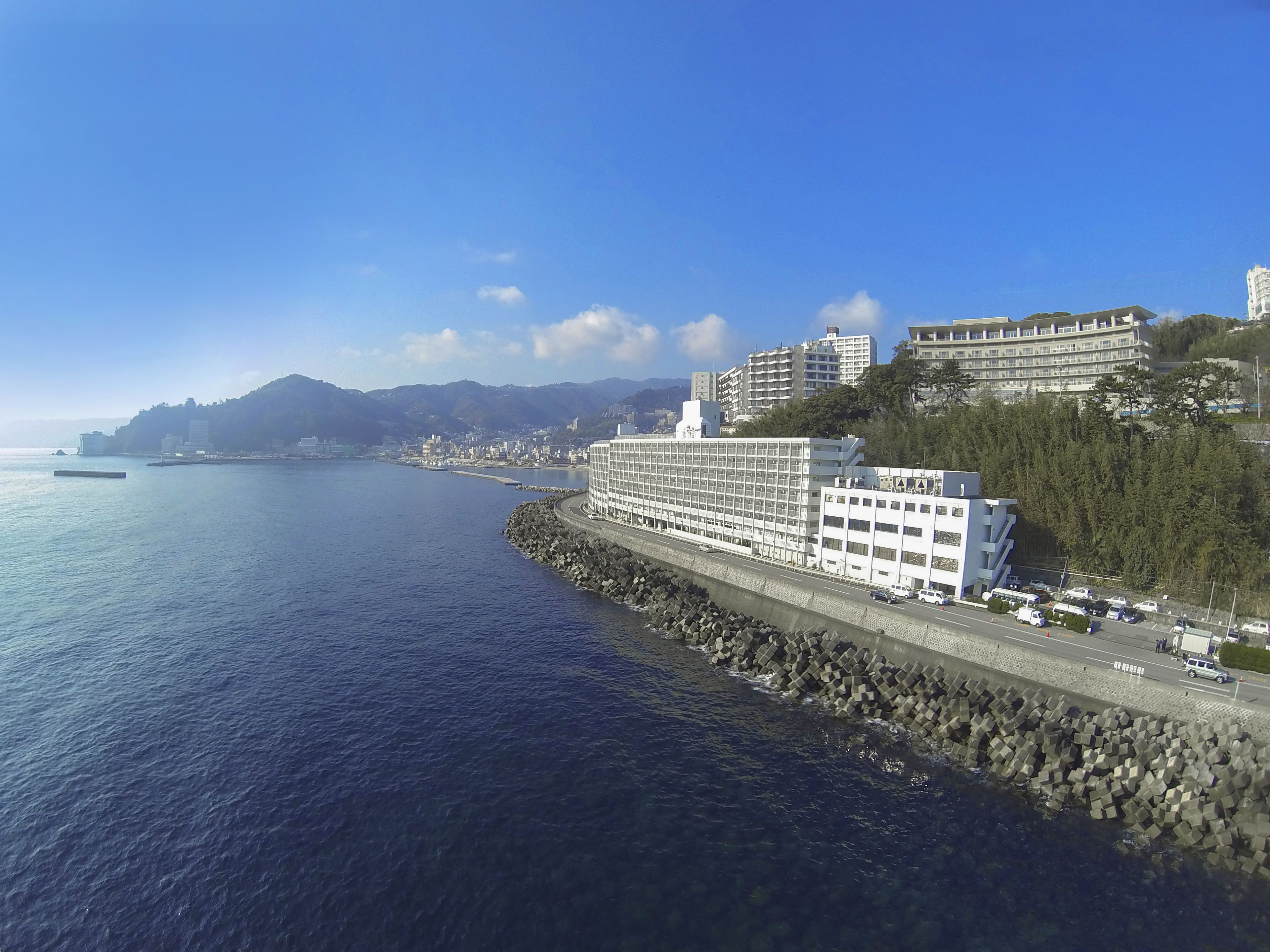 Ein Küstenhotel mit einem großen Gebäude, einer felsigen Küstenlinie und freiem Blick auf das Meer.