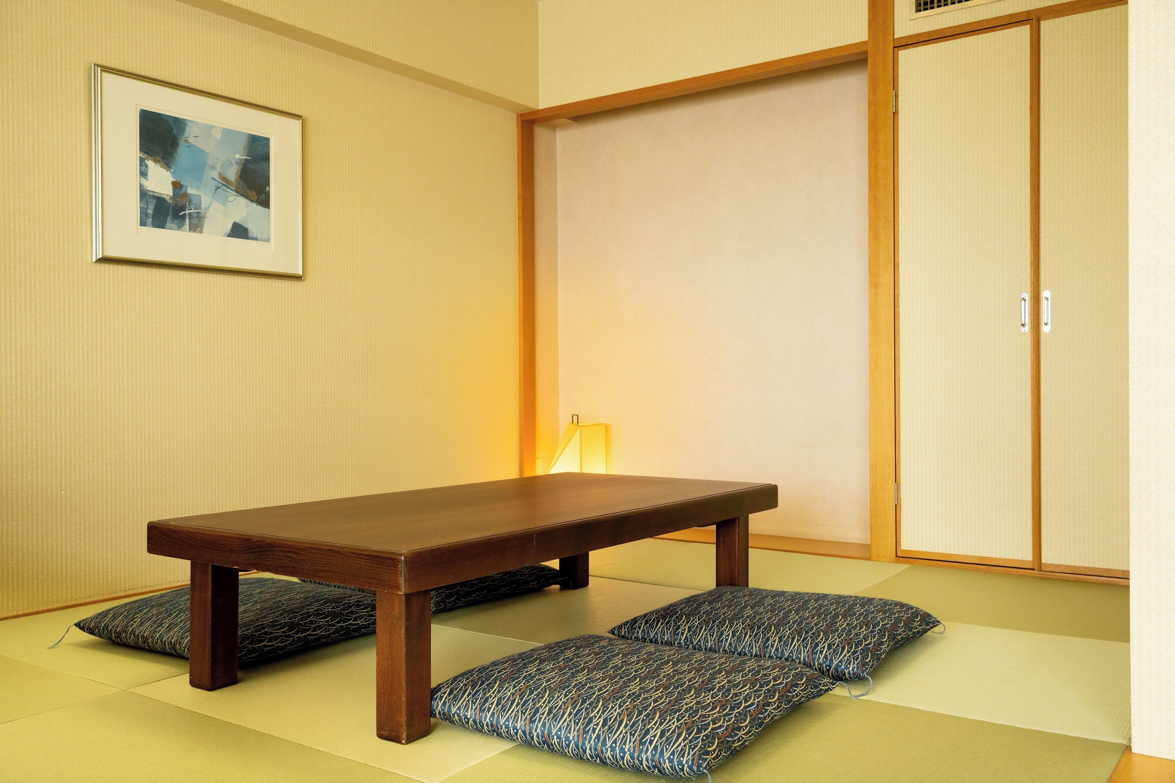 A traditional Japanese room with tatami flooring, a low wooden table, and a sliding door.