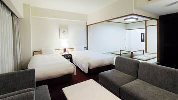 A hotel room with two beds, a sofa, a small table, and a mirror.