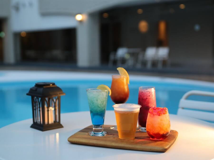 Mesa junto a la piscina con bebidas y una linterna.