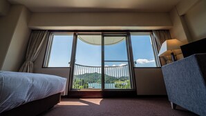 A hotel room with a bed, a chair, a large window with a view of a lake and mountains, and a balcony with a railing. - Resorpia Kumihama (Kyotango)