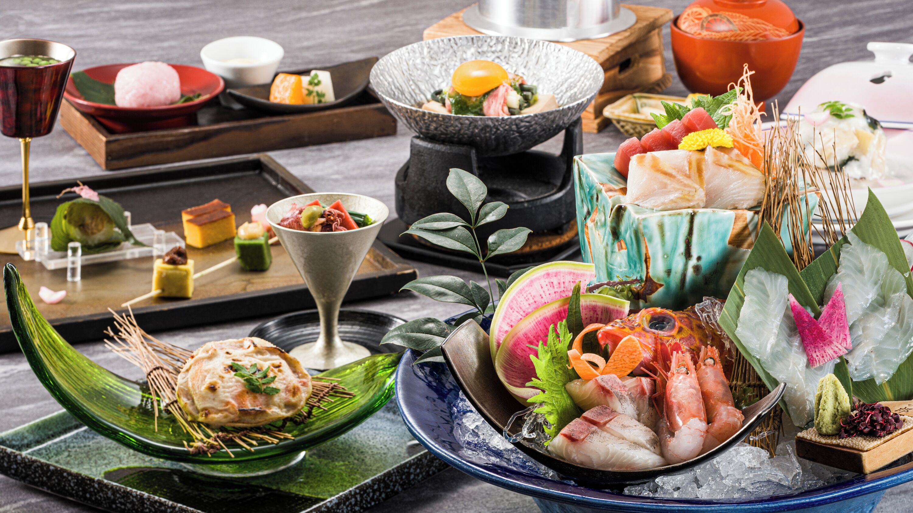 A variety of dishes and drinks on a table, including seafood, vegetables, and a hot pot.