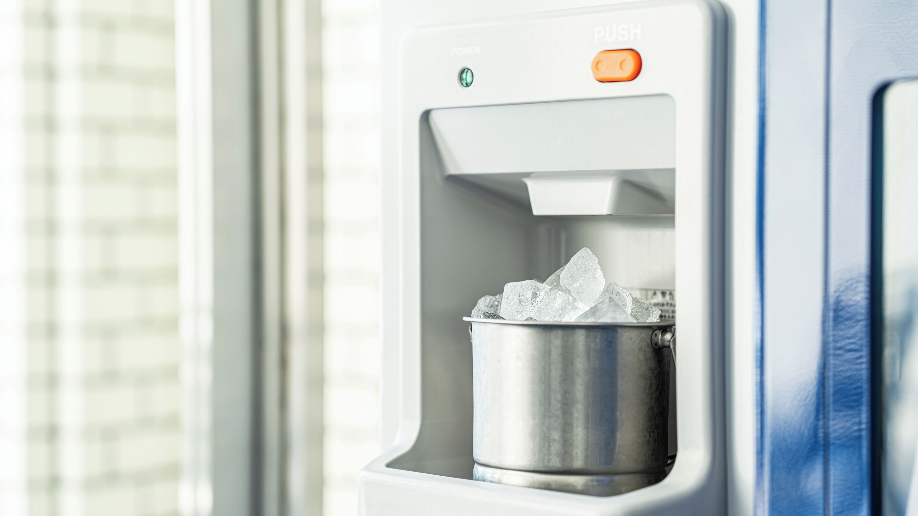 A water dispenser with ice cubes, a power button, and a push button.