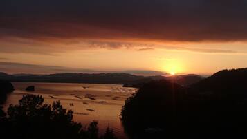 Ein Sonnenuntergang über einem Gewässer mit Bergen in der Ferne und einem klaren Himmel.