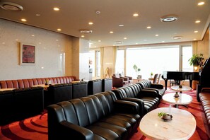 A hotel lobby with leather seating, a grand piano, and large windows. - Resorpia Kumihama (Kyotango)