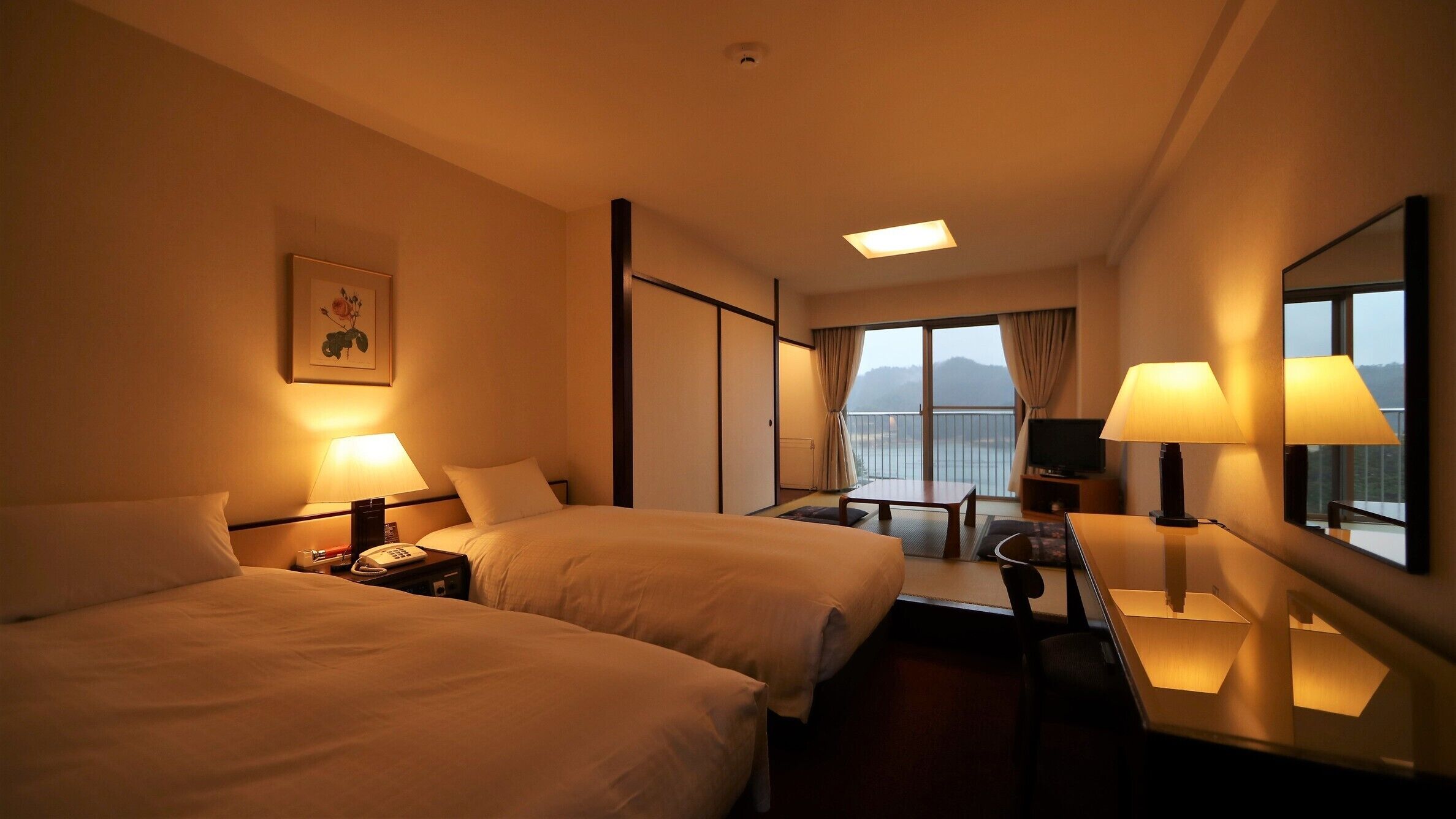 A hotel room with two beds, a desk, a chair, a television, and a large window with a view.